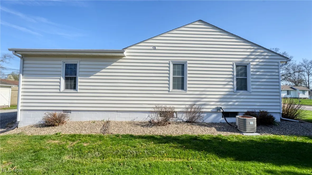 View of side of property with a yard, central AC unit, and crawl space
