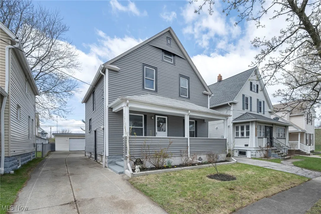 View of front of home with a porch, an outbuilding, a detached garage, and a front yard