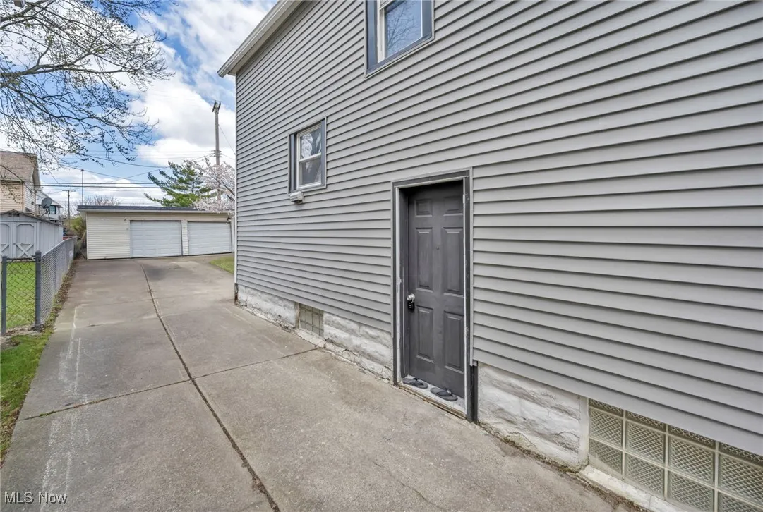 View of side of home featuring an outbuilding, a detached garage, and fence