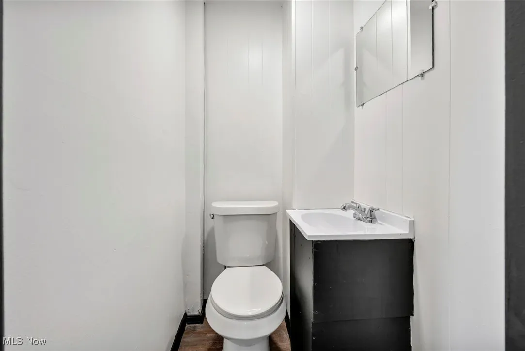 Half bath with vanity, toilet, and wood finished floors