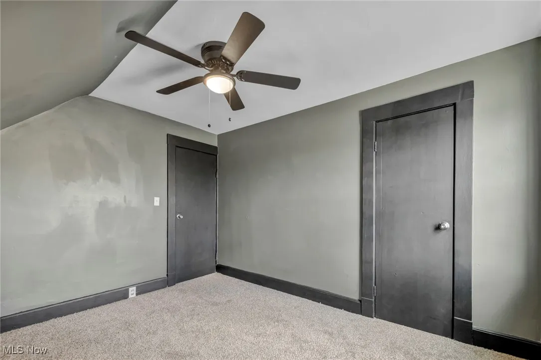 Unfurnished bedroom with lofted ceiling, baseboards, a ceiling fan, and carpet floors