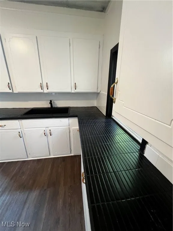 Kitchen with dark countertops, white cabinets, and dark wood-style floors