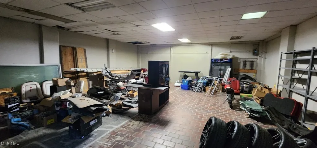 Miscellaneous room featuring a paneled ceiling, visible vents, and brick floor