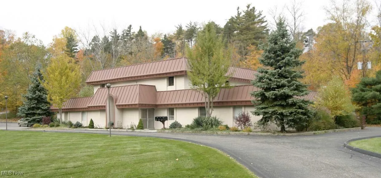 View of front of home with stucco siding, a front yard, aphalt driveway, a standing seam roof, and metal roof