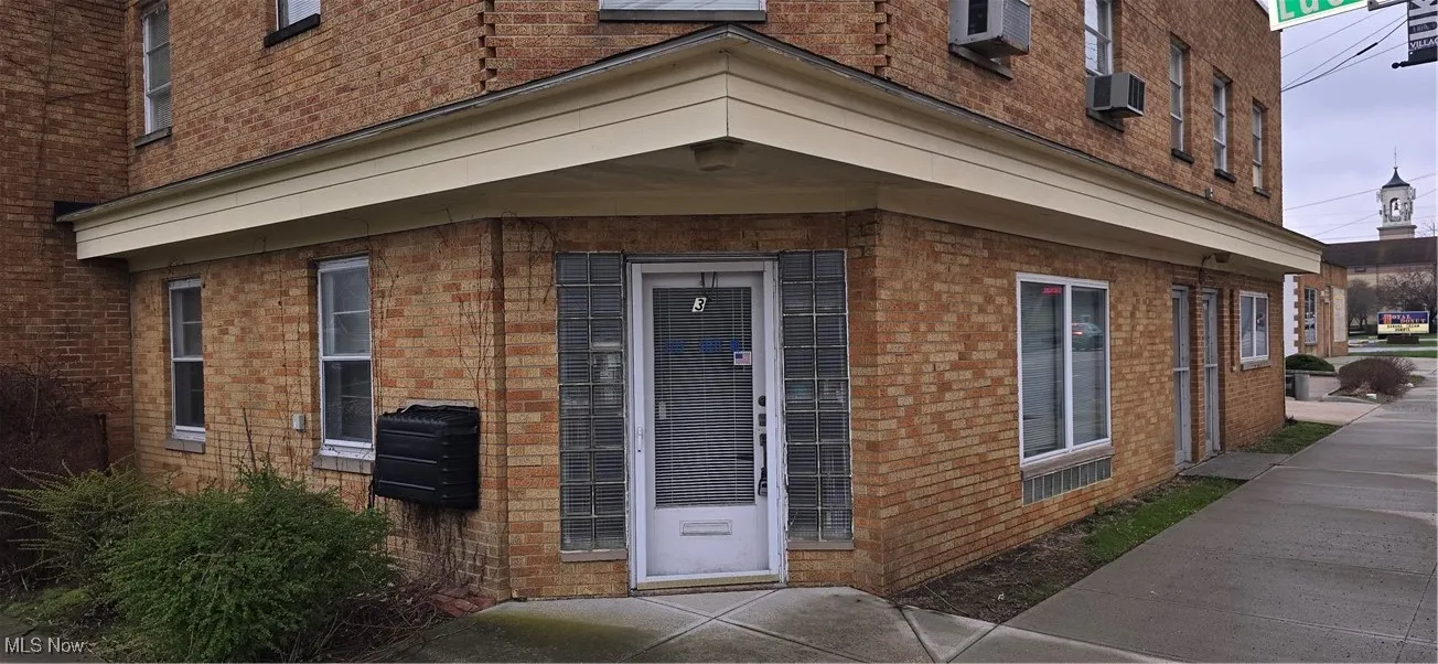 Entrance to property with a wall mounted AC and brick siding