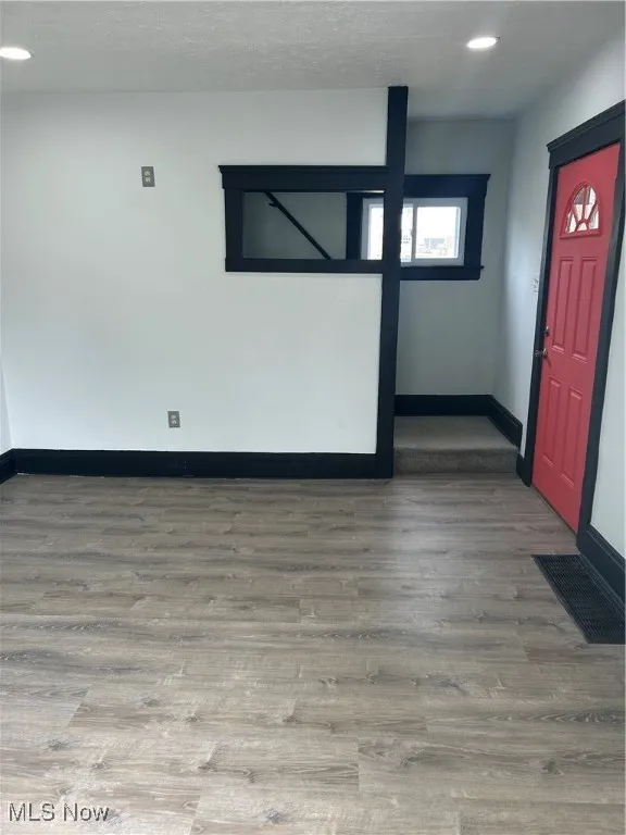Empty room with visible vents, baseboards, a textured ceiling, and wood finished floors