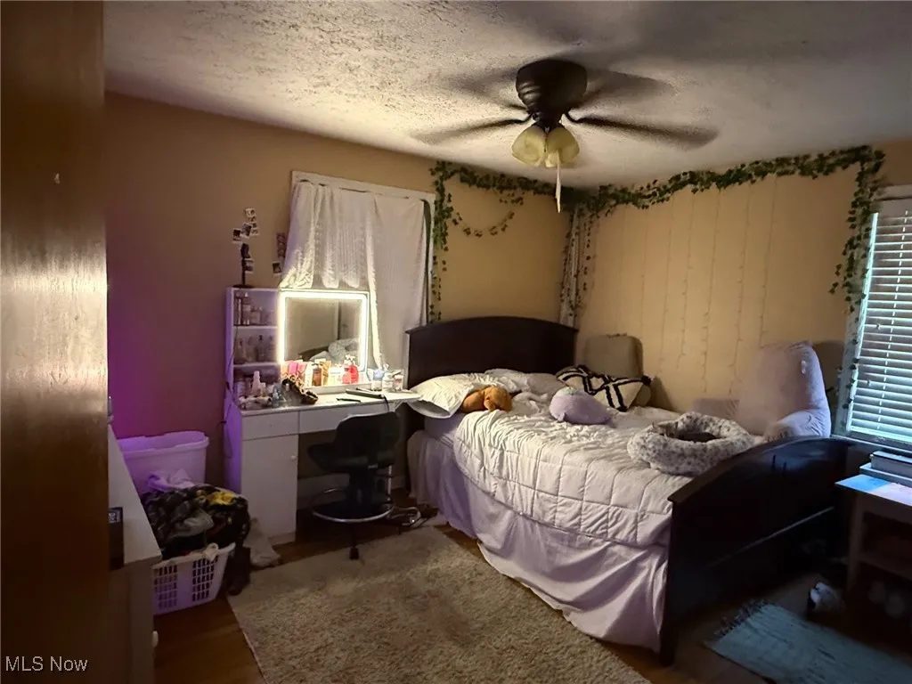 Bedroom featuring ceiling fan, wood finished floors, and a textured ceiling