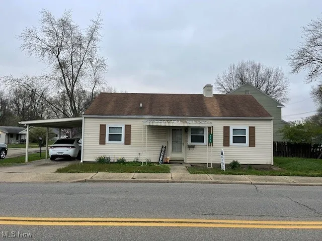 View of front of home with a chimney, concrete driveway, and an attached carport