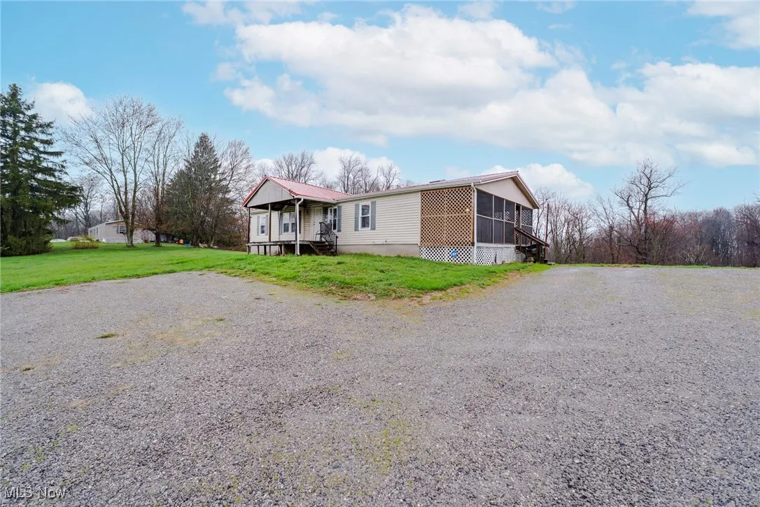 Manufactured / mobile home featuring a front yard, driveway, and a sunroom