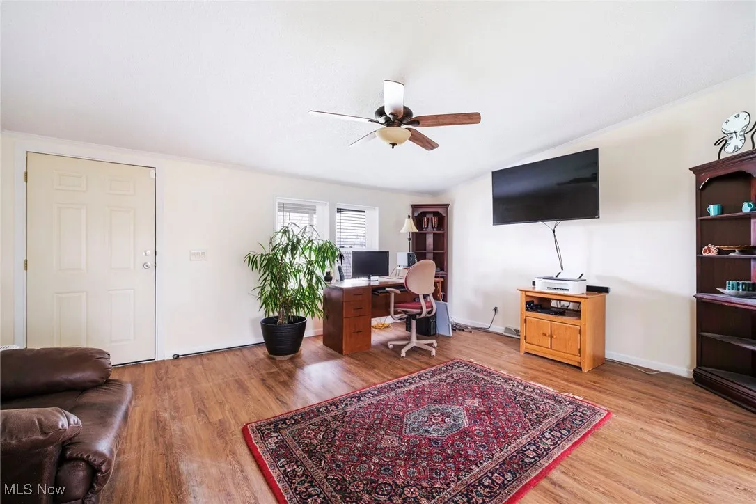 Office space with baseboards, light wood-type flooring, and a ceiling fan