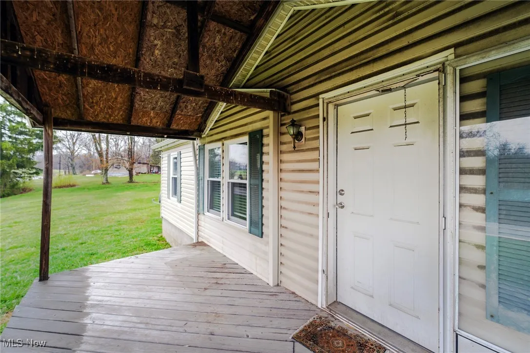 Property entrance with a deck and a lawn