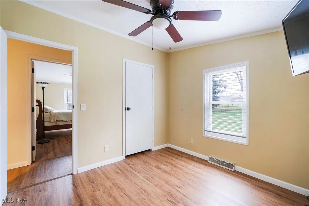 Unfurnished bedroom featuring crown molding, light wood finished floors, and visible vents