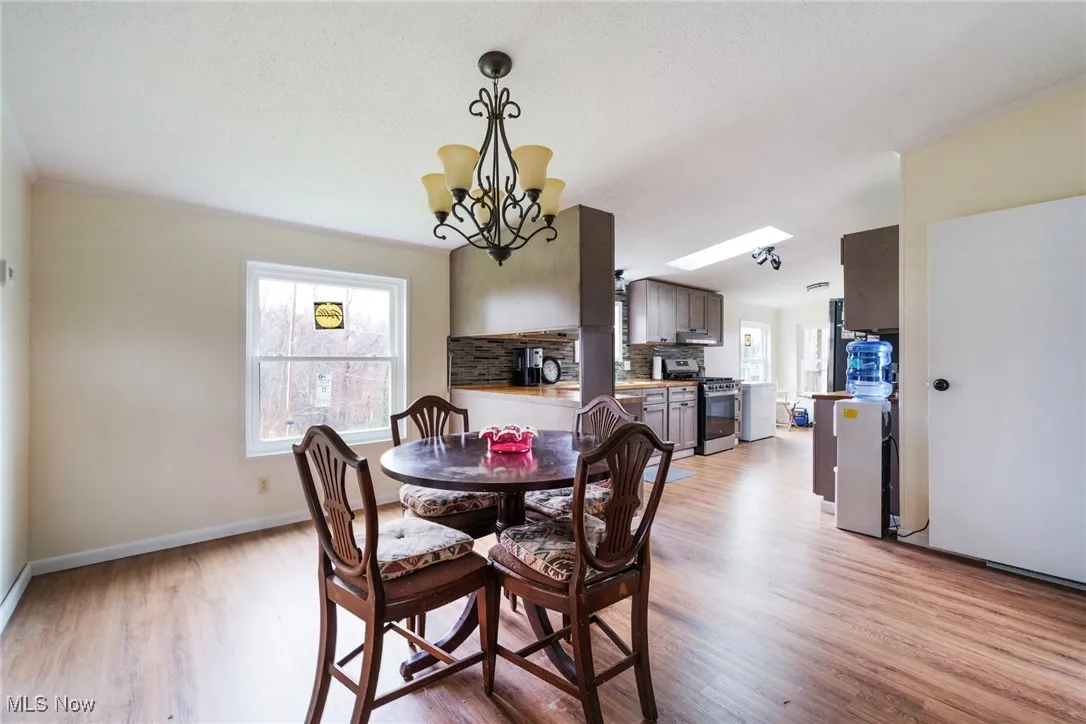 Dining room featuring plenty of natural light, light wood-style flooring, baseboards, and an inviting chandelier