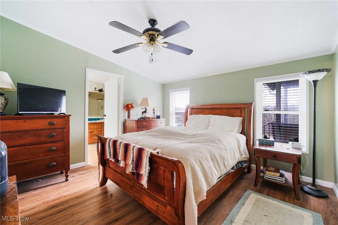 Bedroom featuring baseboards, a ceiling fan, vaulted ceiling, and wood finished floors