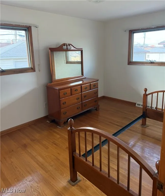 Bedroom with light hardwood / wood-style flooring and multiple windows