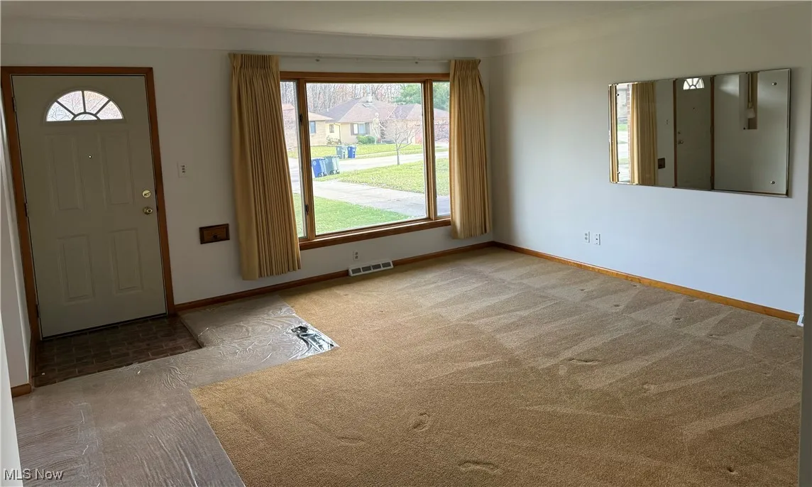 Entrance foyer with light colored carpet