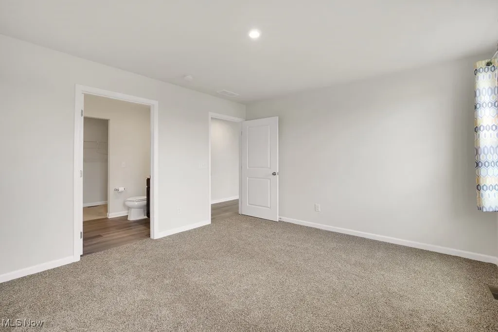 Unfurnished bedroom with visible vents, baseboards, and carpet