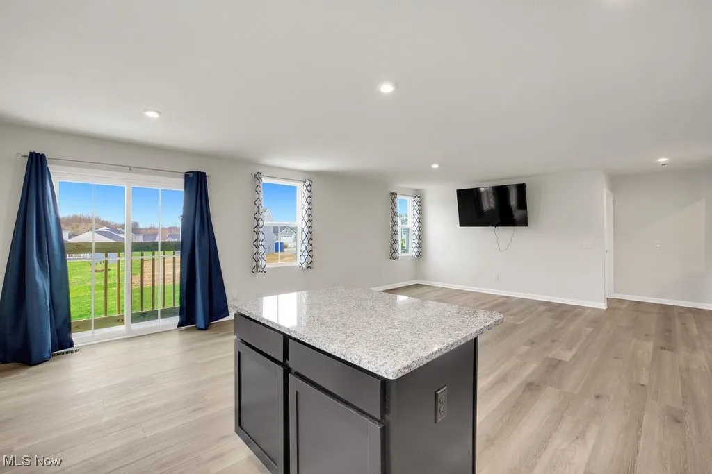 Kitchen featuring light wood-style flooring, recessed lighting, a kitchen island, and baseboards