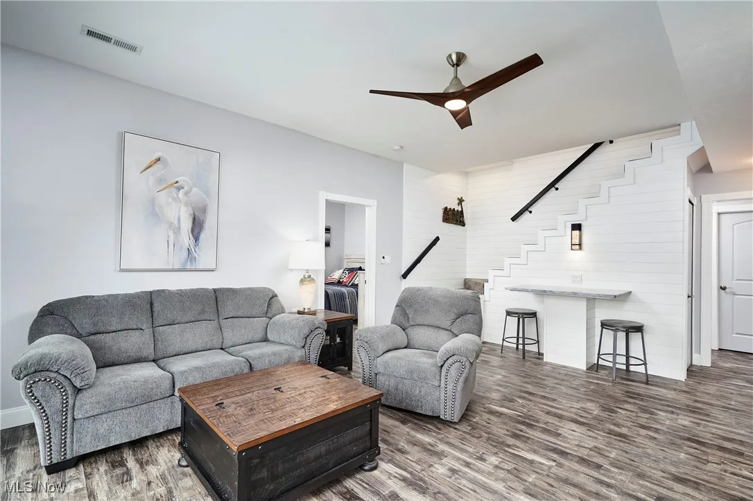 Living area featuring stairway, visible vents, wood finished floors, and ceiling fan