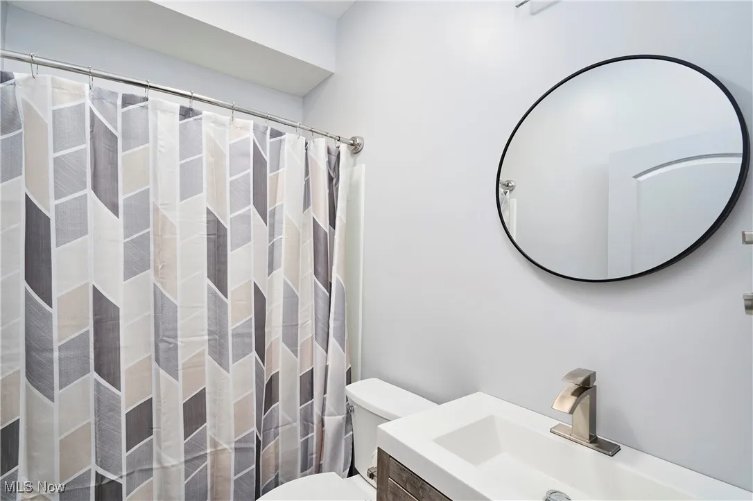 Full bathroom with toilet, a shower with shower curtain, and vanity