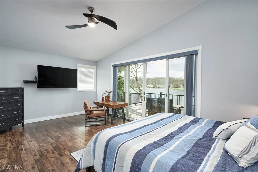 Bedroom featuring baseboards, ceiling fan, dark wood-type flooring, high vaulted ceiling, and access to outside