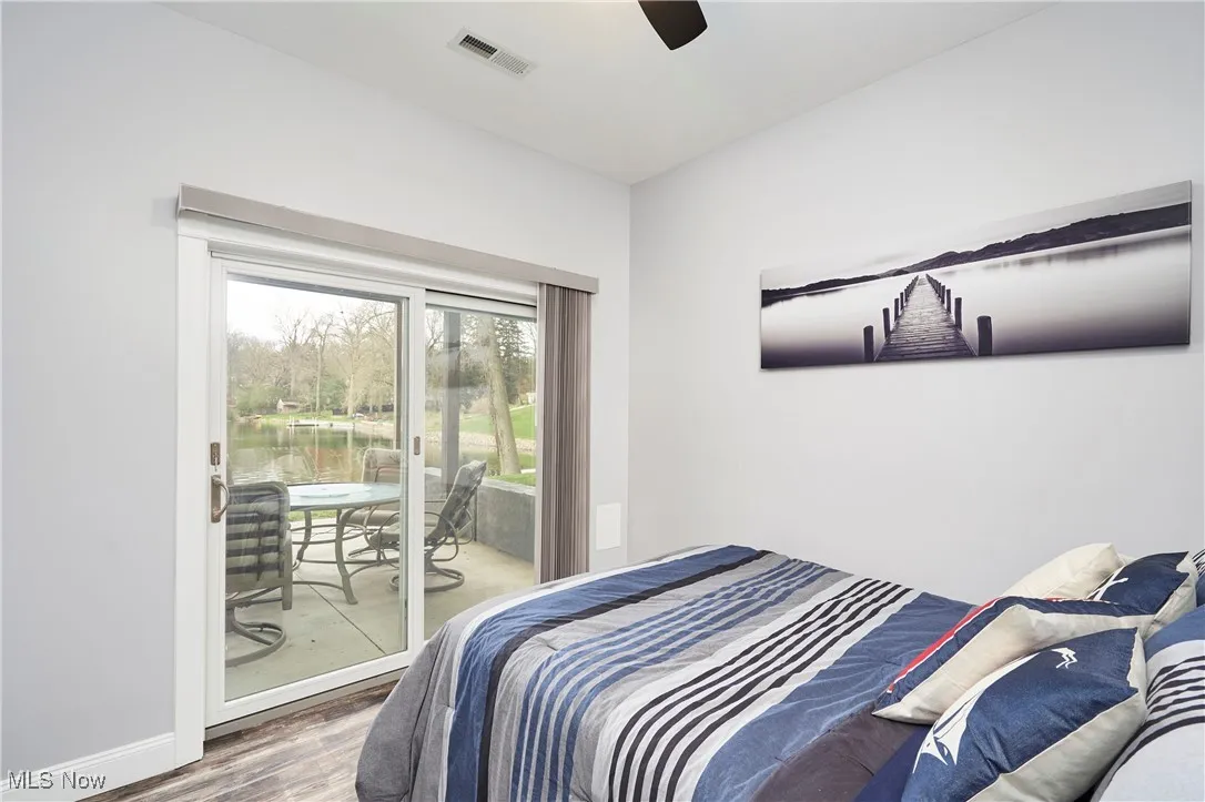Bedroom with visible vents, baseboards, a ceiling fan, wood finished floors, and access to outside