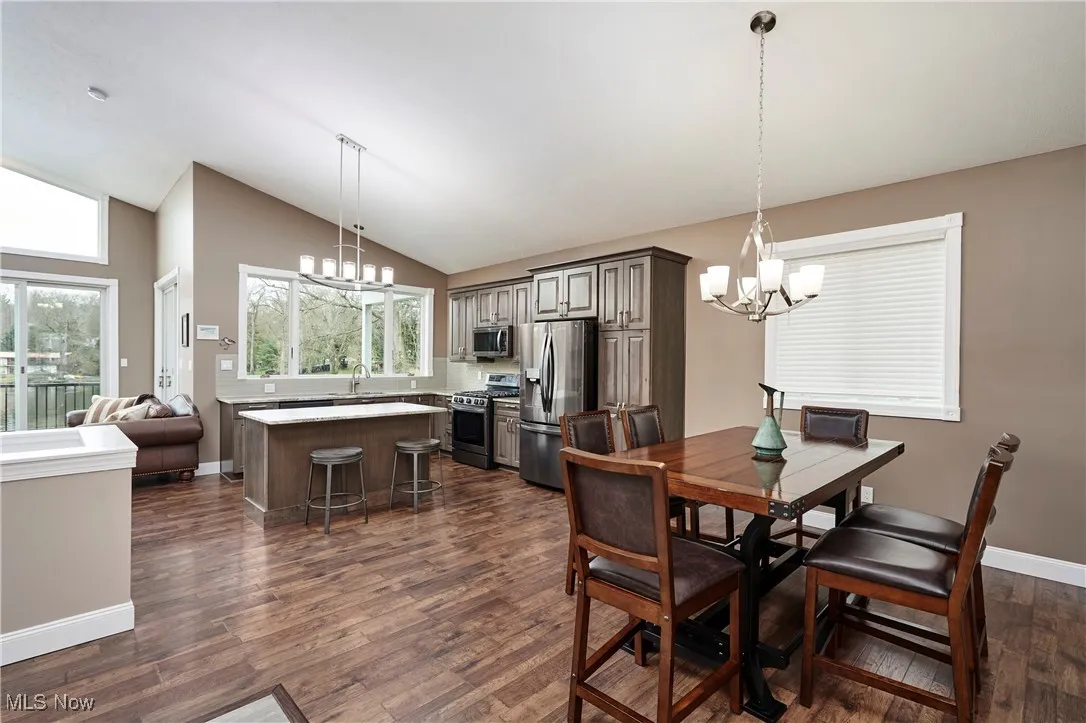 Dining area with baseboards, high vaulted ceiling, a notable chandelier, and dark wood finished floors