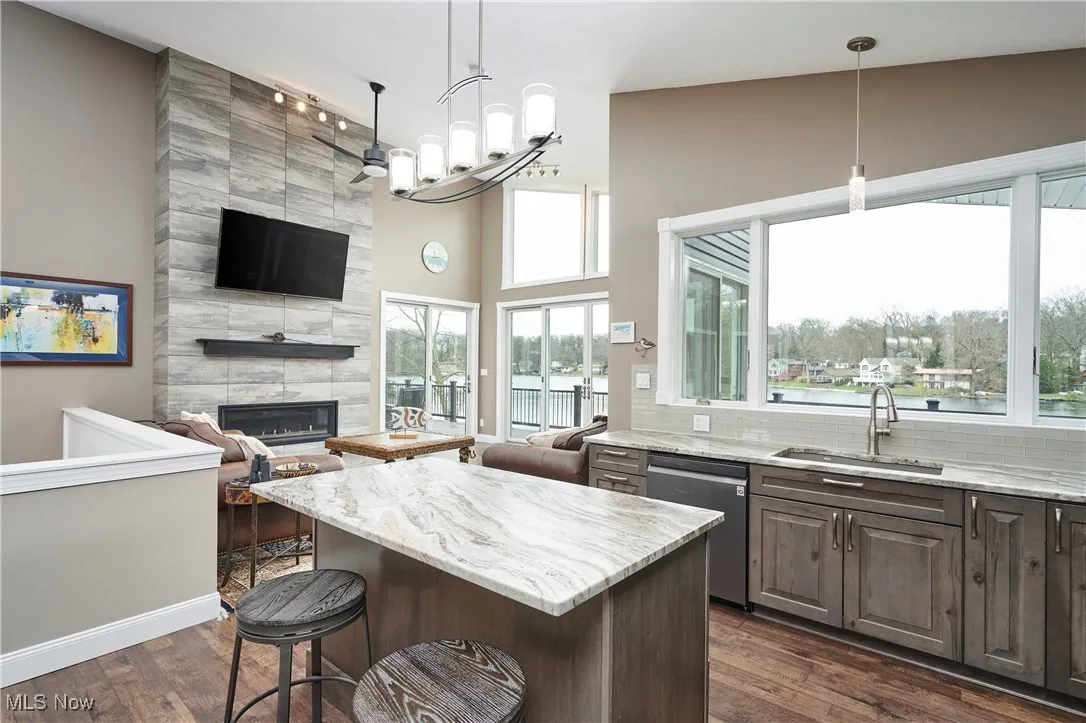 Kitchen featuring a sink, open floor plan, stainless steel dishwasher, and a fireplace