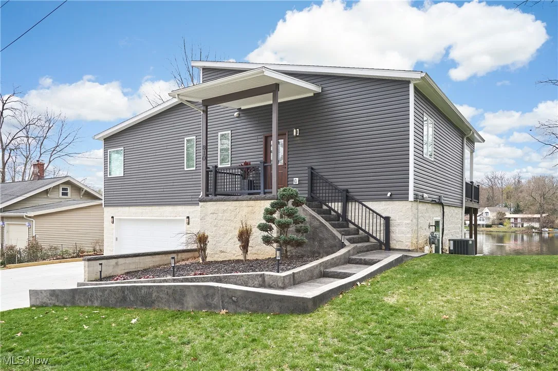 View of front of property featuring a front yard, an attached garage, central AC, and driveway