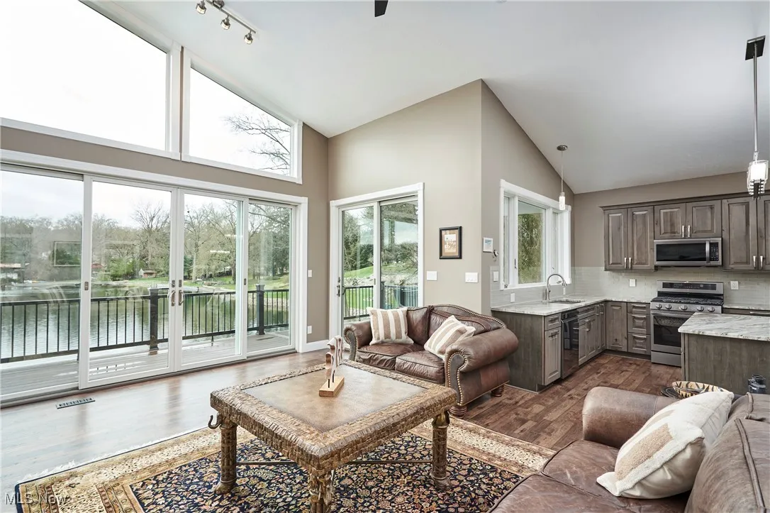 Living area featuring high vaulted ceiling, dark wood-style floors, visible vents, and a water view