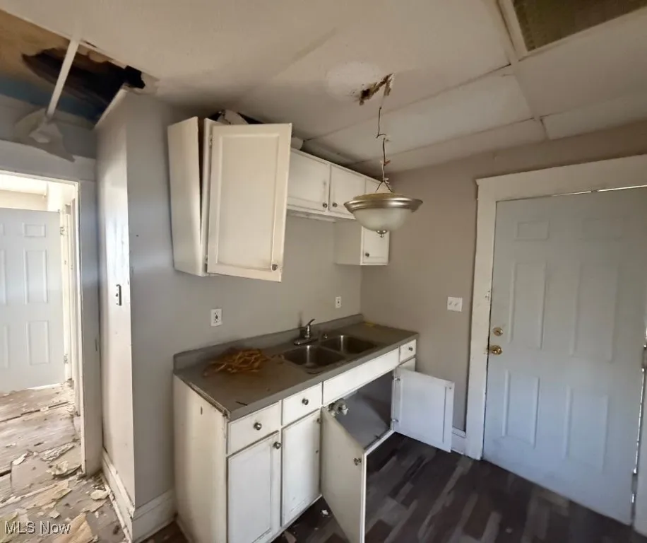 Kitchen featuring dark wood-style floors, white cabinetry, a sink, and dark countertops