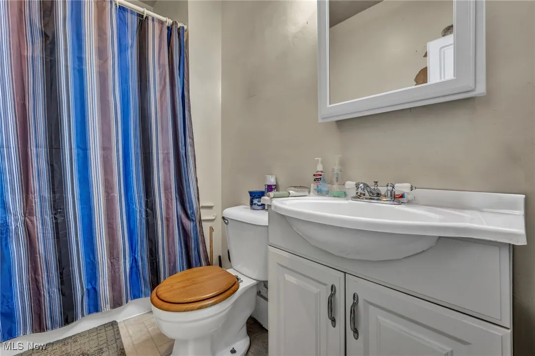 Bathroom featuring toilet, vanity, and a shower with curtain