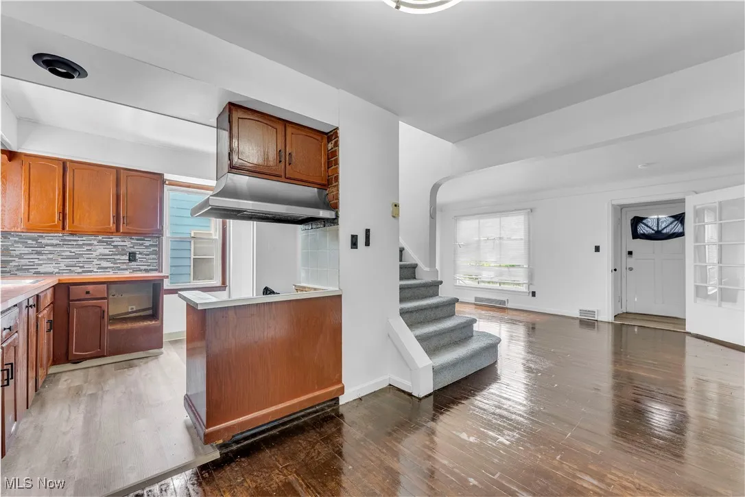 Kitchen with hardwood / wood-style floors, tasteful backsplash, light countertops, and brown cabinets