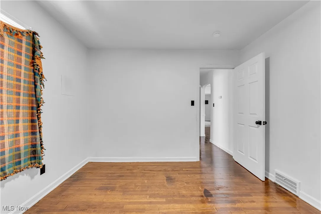 Spare room with wood finished floors and arched walkways
