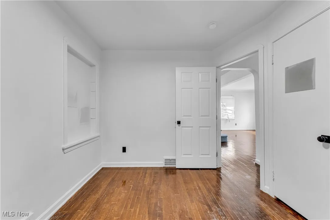 Spare room with arched walkways and hardwood / wood-style floors