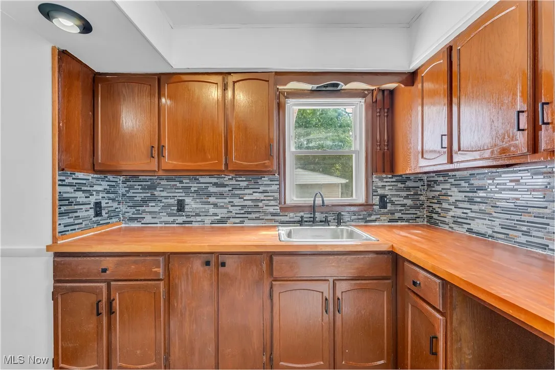Kitchen featuring wood counters, brown cabinetry, and tasteful backsplash
