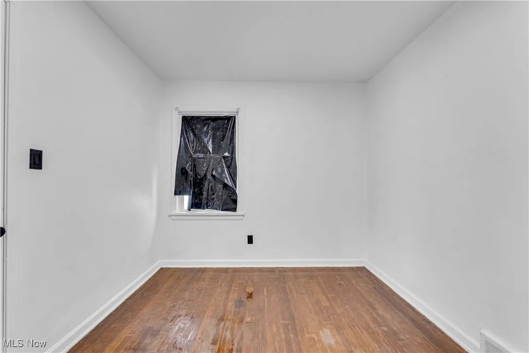 Unfurnished room with wood finished floors and baseboards