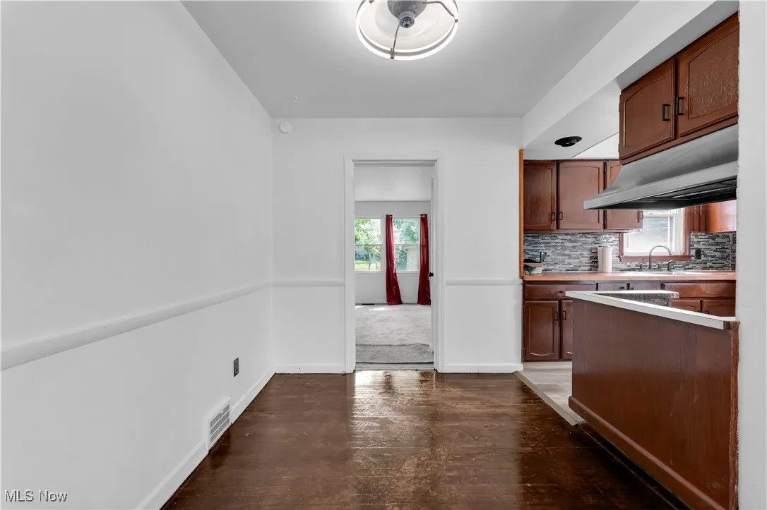 Kitchen featuring dark wood-style floors, healthy amount of natural light, under cabinet range hood, and light countertops
