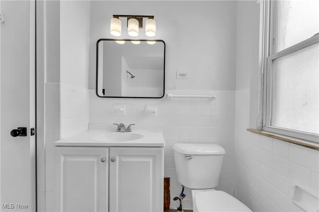 Bathroom featuring tile walls, vanity, and a wainscoted wall