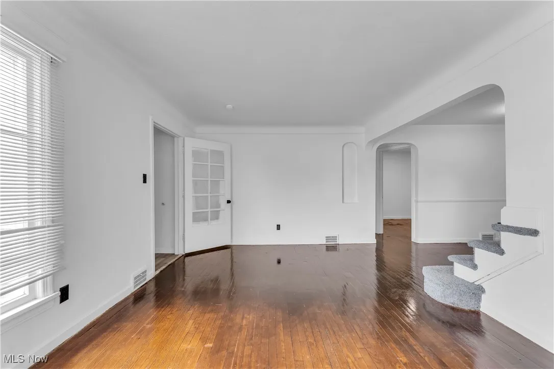 Spare room with arched walkways, hardwood / wood-style flooring, and stairway