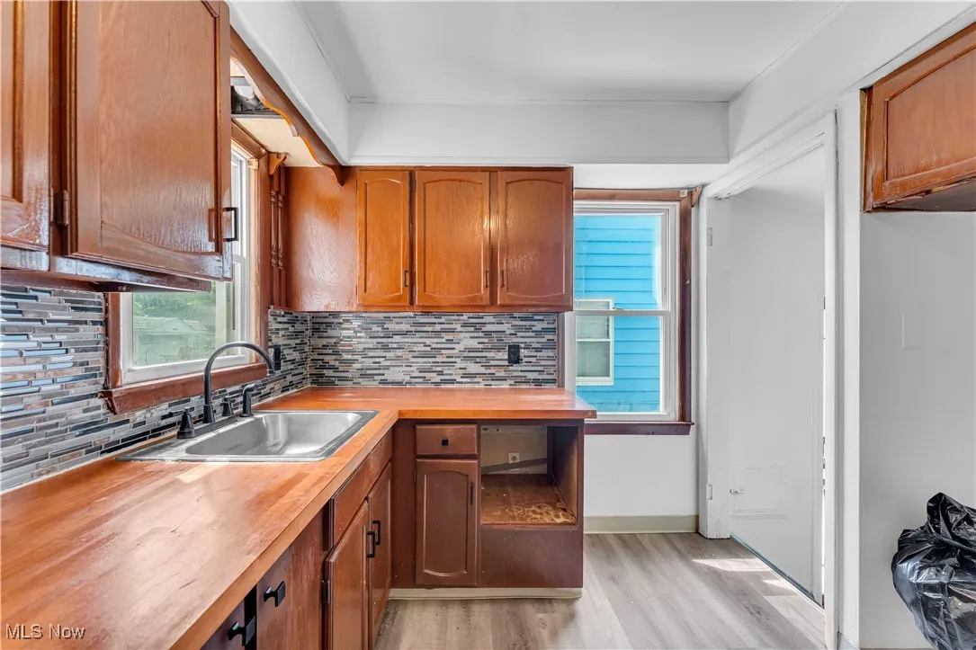 Kitchen with wood counters, backsplash, light wood-style flooring, and brown cabinetry