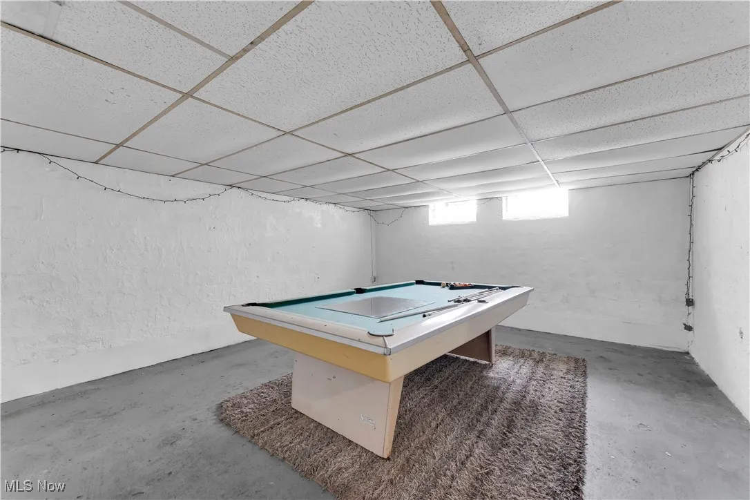 Recreation room with a drop ceiling, unfinished concrete floors, and billiards