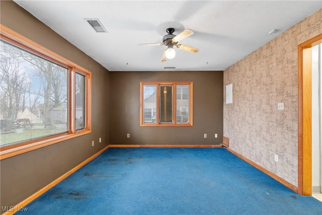 Carpeted empty room featuring visible vents, baseboards, and a ceiling fan