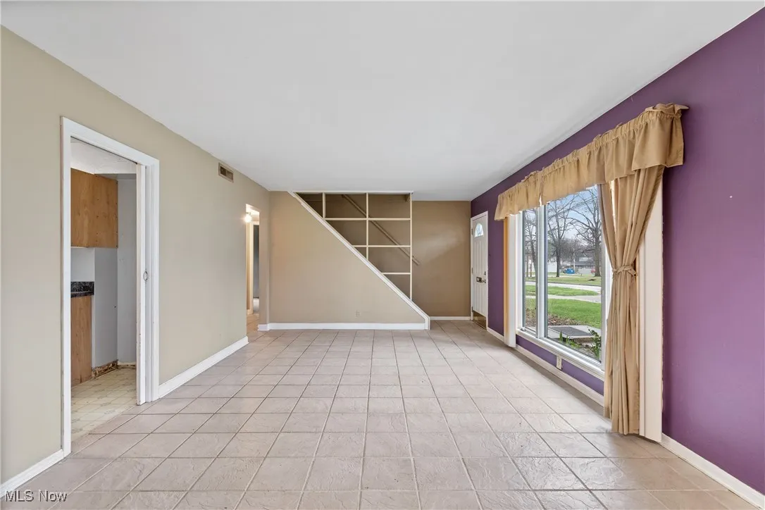 Spare room with stairs, visible vents, and baseboards