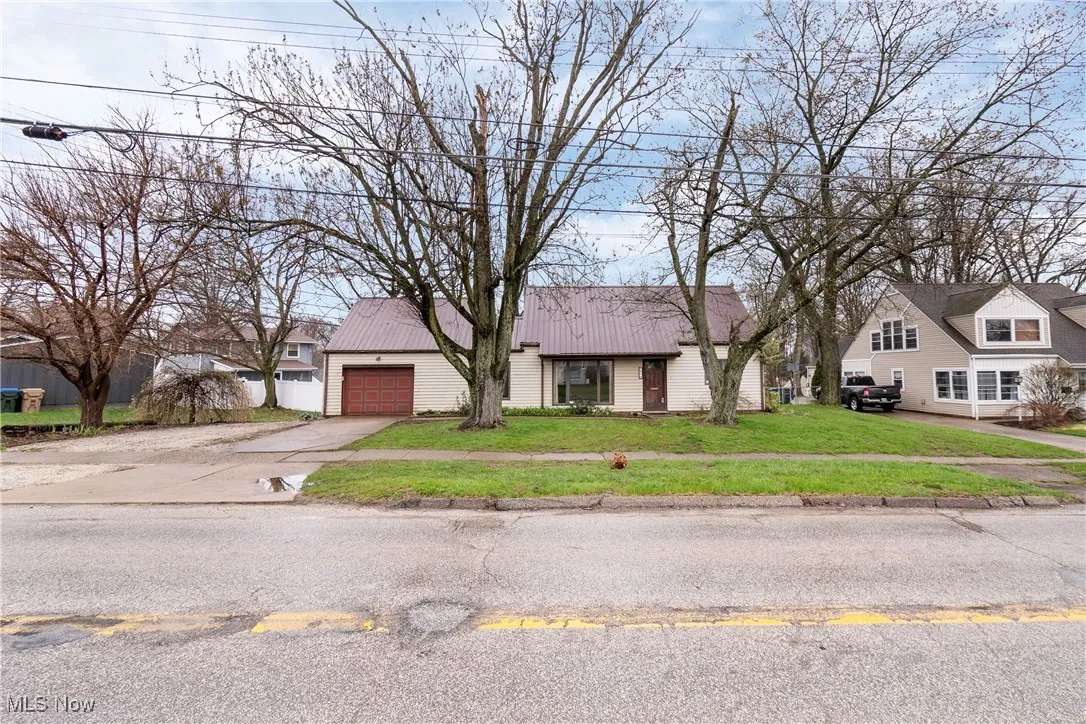 View of front facade with concrete driveway, a front yard, metal roof, and a garage