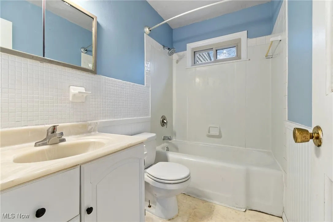 Full bath featuring toilet, shower / tub combination, vanity, and wainscoting
