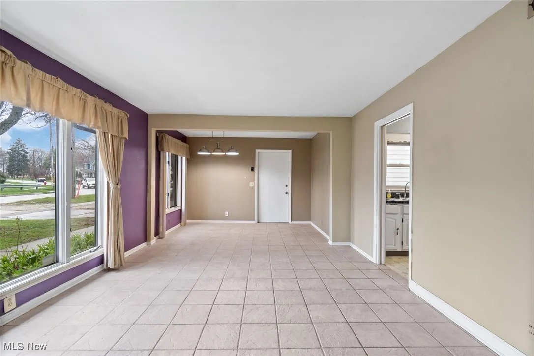 Spare room featuring a chandelier, a wealth of natural light, light tile patterned floors, and baseboards