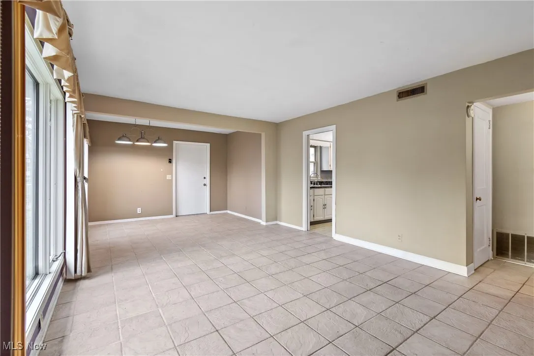 Unfurnished room featuring visible vents, a wealth of natural light, and light tile patterned floors