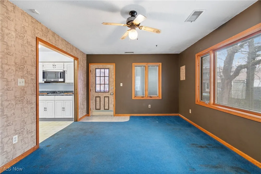 Unfurnished room featuring light colored carpet, baseboards, a ceiling fan, and visible vents