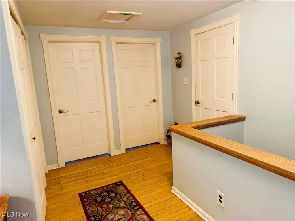 Corridor featuring baseboards, an upstairs landing, light wood-type flooring, and attic access